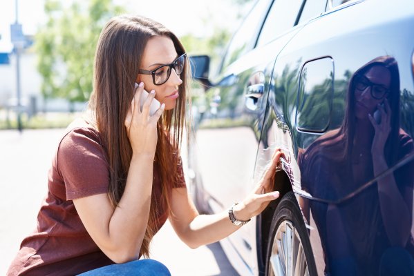 carchex features extended car warranty woman down by the car talking on mobile phone 